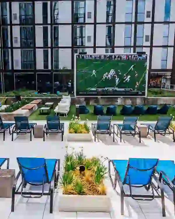 Hawks game playing on outdoor jumbotron with lounge seating next to planters